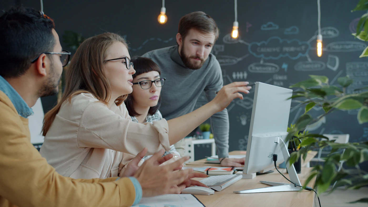 Team im Büro im Gespräch an einem Arbeitsplatz, sinnbildlich für die Zusammenarbeit im Planungsprozess